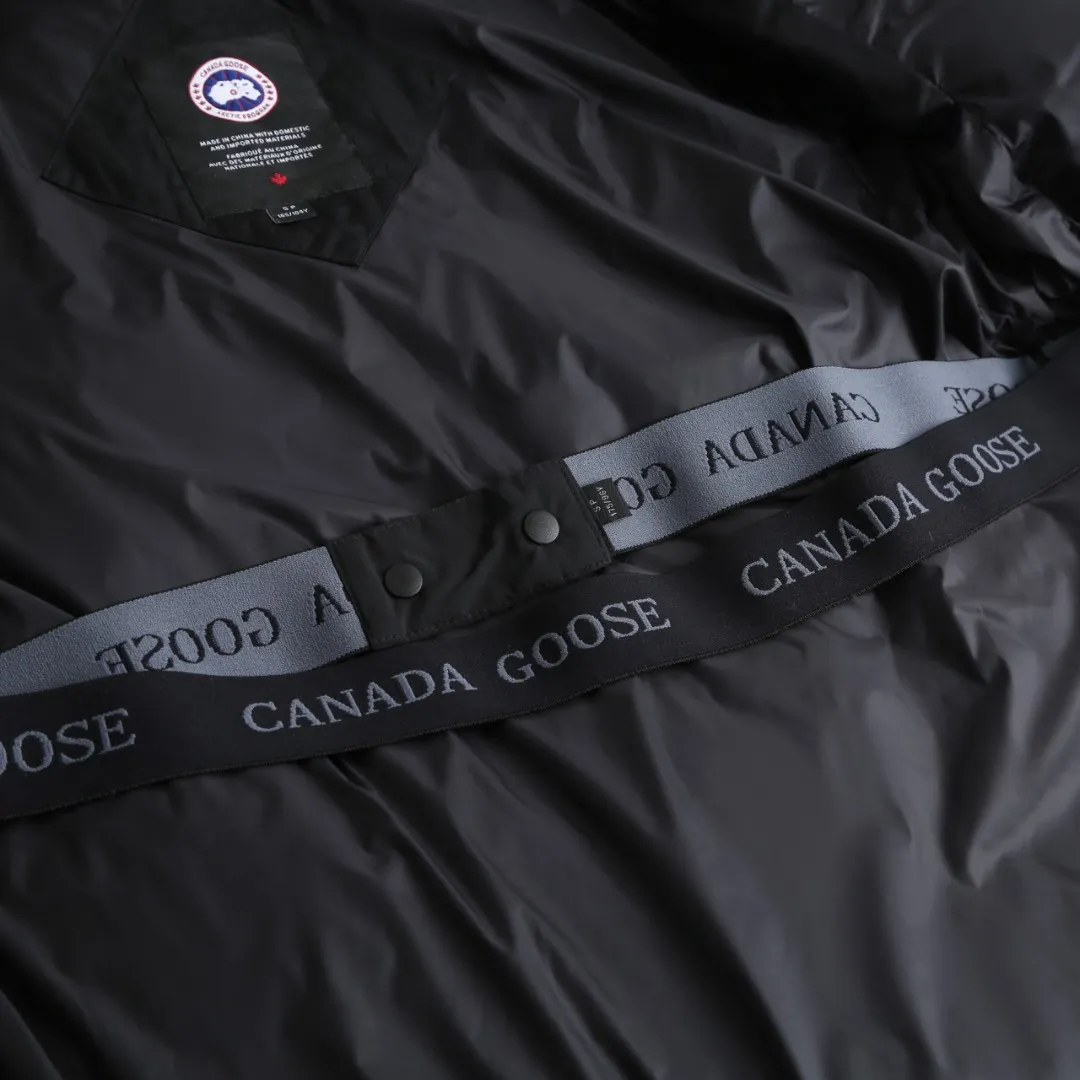 P980 Canada Goose hooded down jacket Fabric selection: Weaved with 400T high-count yarn. After special water-repellent treatment, the surface forms a lotus leaf effect - raindrops will slide down in beads, and snow particles will fall off when touched. The tear resistance reaches 200N (approximately 20kg load-bearing), the light gray matte texture breaks the stereotype of "outdoor clothing = hardcore", and the soft luster presents a high-end matte effect under urban neon lights, seamlessly switching scenes from ski resorts to CBD office buildings.  Process 1: Use polyester woven ribbons as the base, and use high-precision computer embroidery to decorate the brand letters on the ribbons. The edges of the pattern are clear, the stitches are fine and even, and multiple layers of embroidery threads are stacked to enhance the three-dimensional effect.  Process 2: Precision thread reinforcement to prevent velvet drilling and ensure that the fluffy and resilient elasticity lasts as new.  Details: The embedded cuffs are three-dimensionally woven to form a "wavy" elastic structure, forming natural folds when fitting the wrist, increasing the contact area with the skin, thus improving the windproof effect. At the same time, micro-velvet treatment is added to the inside of the cuffs, which feels like a second layer of skin and avoids friction on the skin from metal zippers or hard fabrics.  90 national standard high-quality white duck down: selected high-loft down, weighing 240g, light and warm, with excellent temperature locking performance and good resilience.  Accessories: 1:1 customized armband, 1:1 customized zipper pendant, 1:1 customized elastic buckle, etc. SIZE: S M L XL